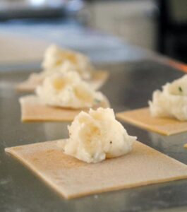 Homemade ravioli being prepared. The filling is sitting on top of the dough, waiting to be rolled up.