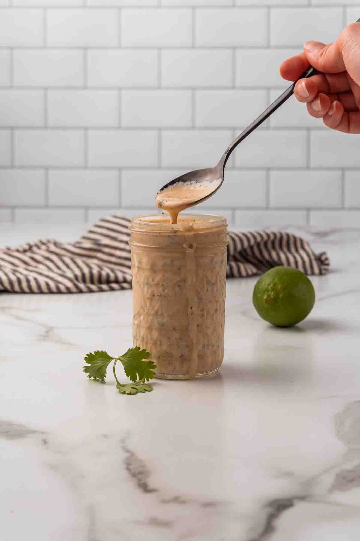 Spooning out the dressing from a jar. 