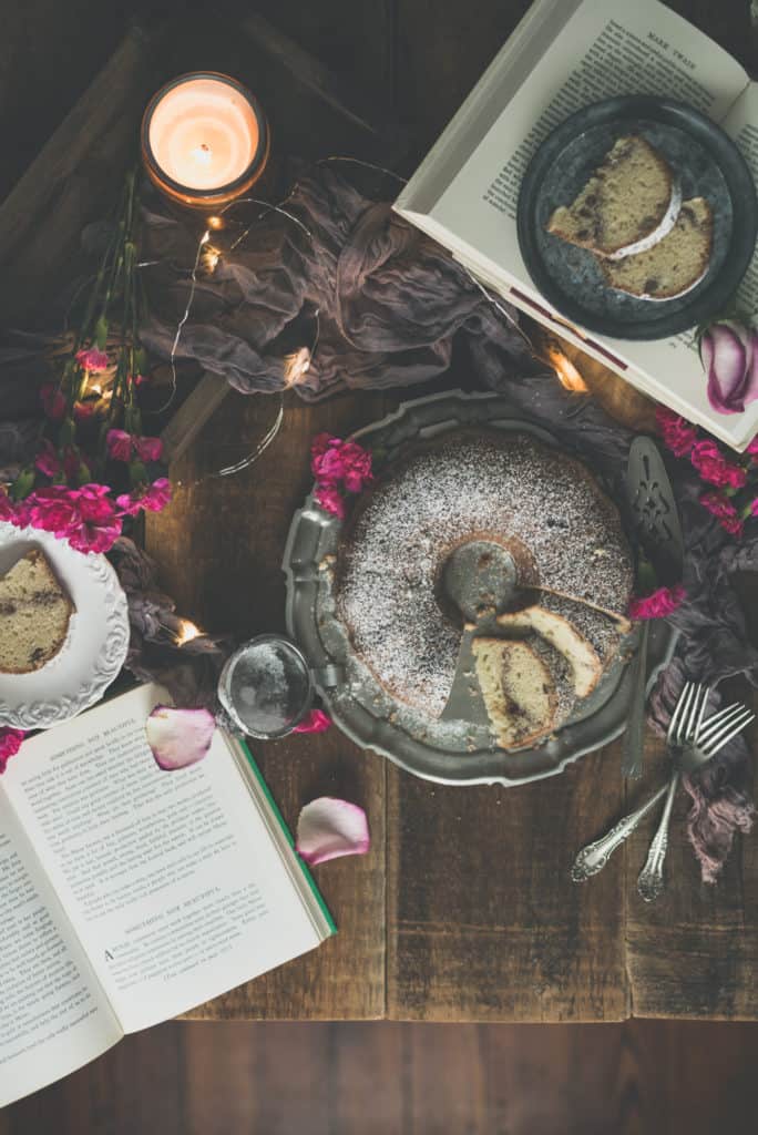 Coffee Cake dusted in powdered sugar seen from above with an open book, flower petals and forks in the scene | Kita Roberts PassTheSushi.com