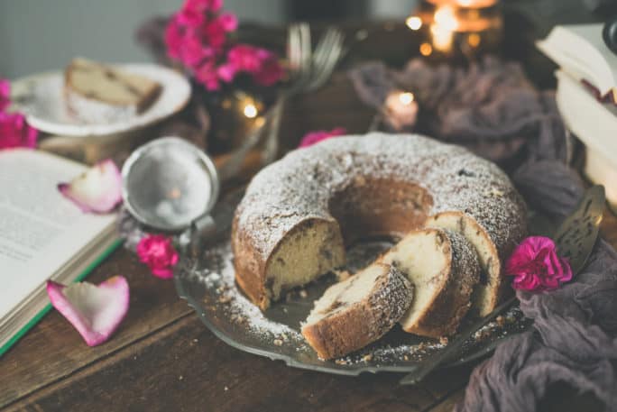 Coffee Cake sliced on a serving tray with flowers and books in the background | Kita Roberts PassTheSushi.com