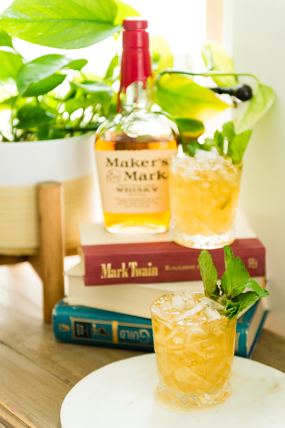 Mint julep in foreground with books and an additional cocktail behind. 