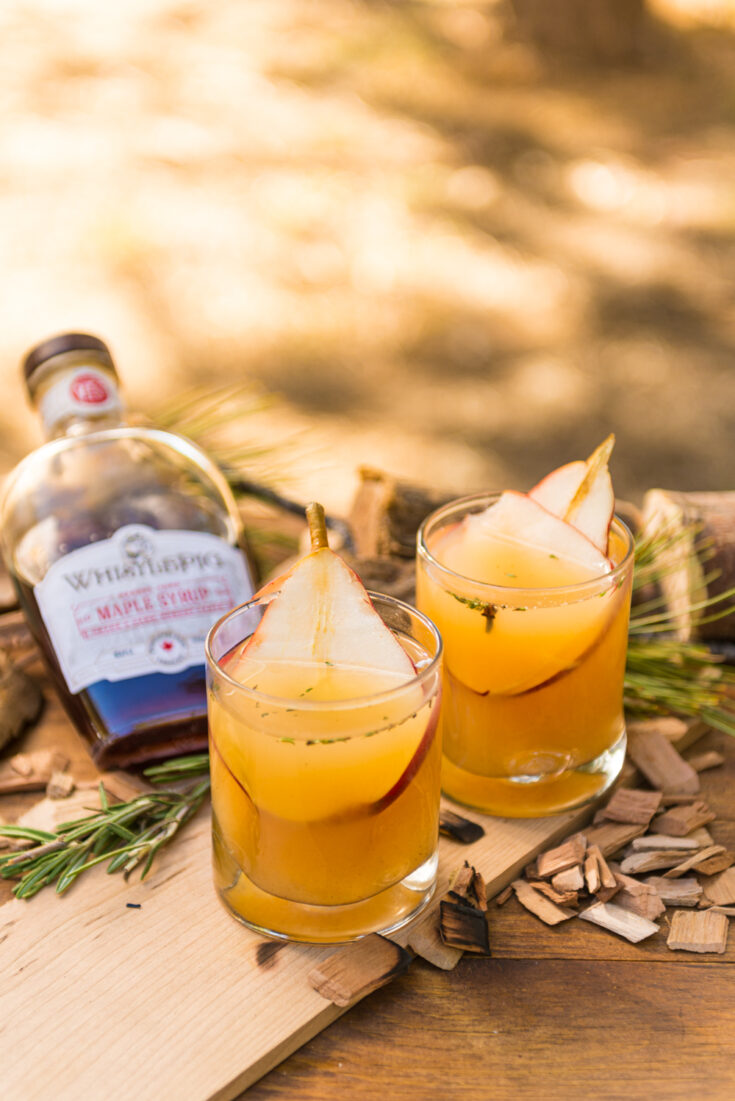 2 glasses of pear white wine sangria with pear slices in each on a wooden board