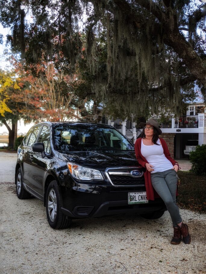 Woman leaning on black subaru forester