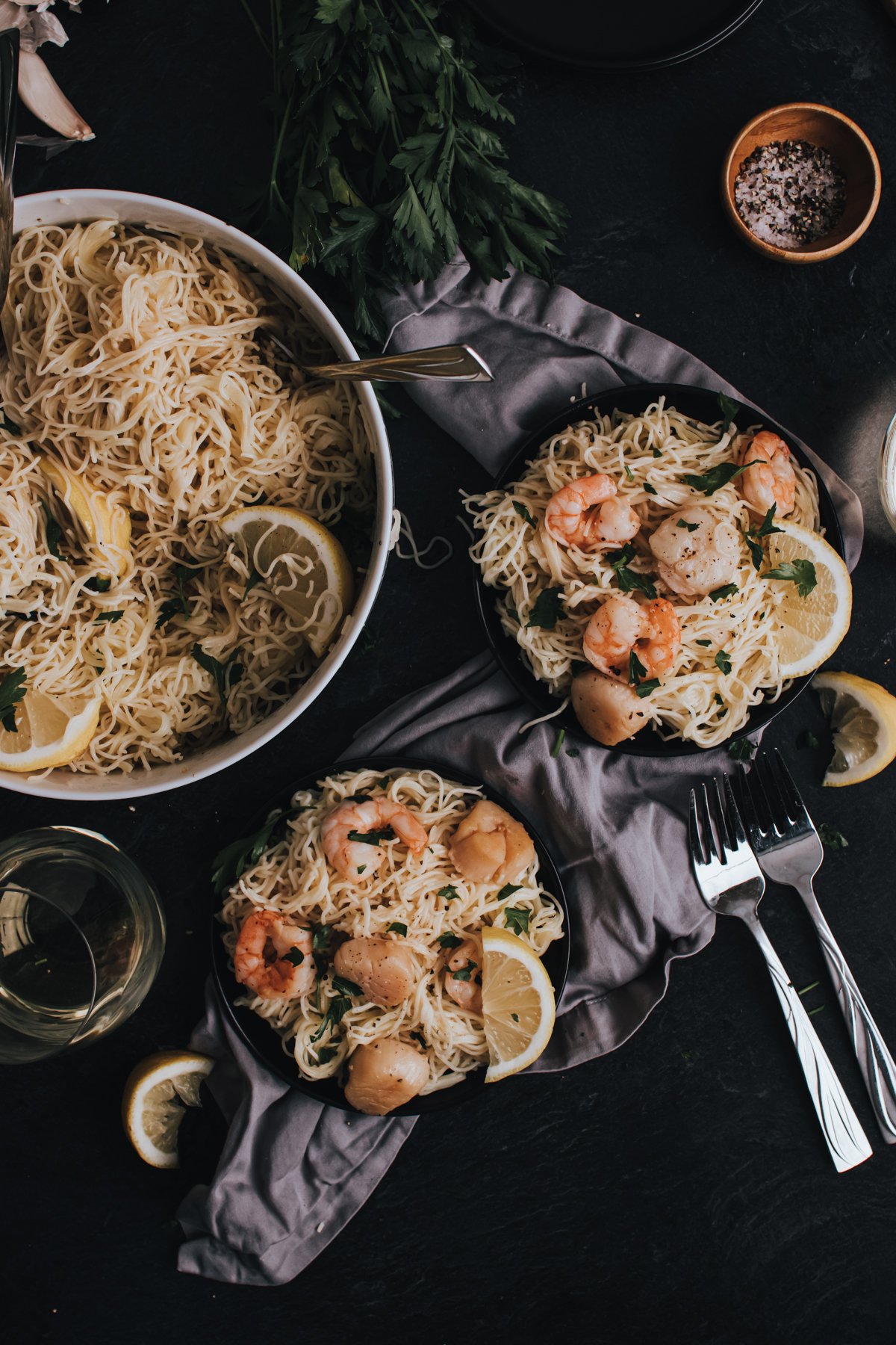 Plates full of this pasta and seafood dish with forks and lemon wedges ready to be enjoyed. 