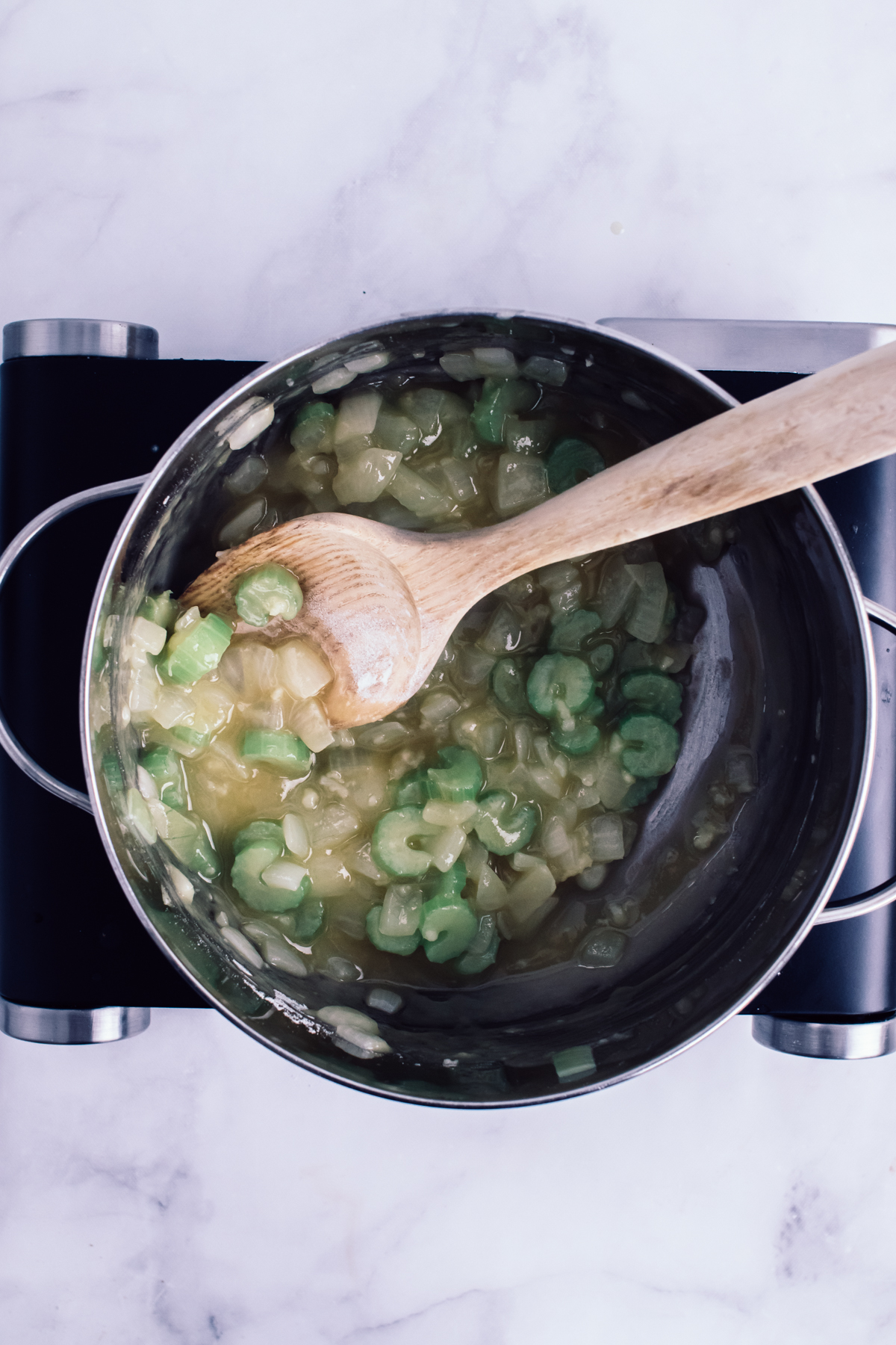 stirring a pot of soup with wooden spoon