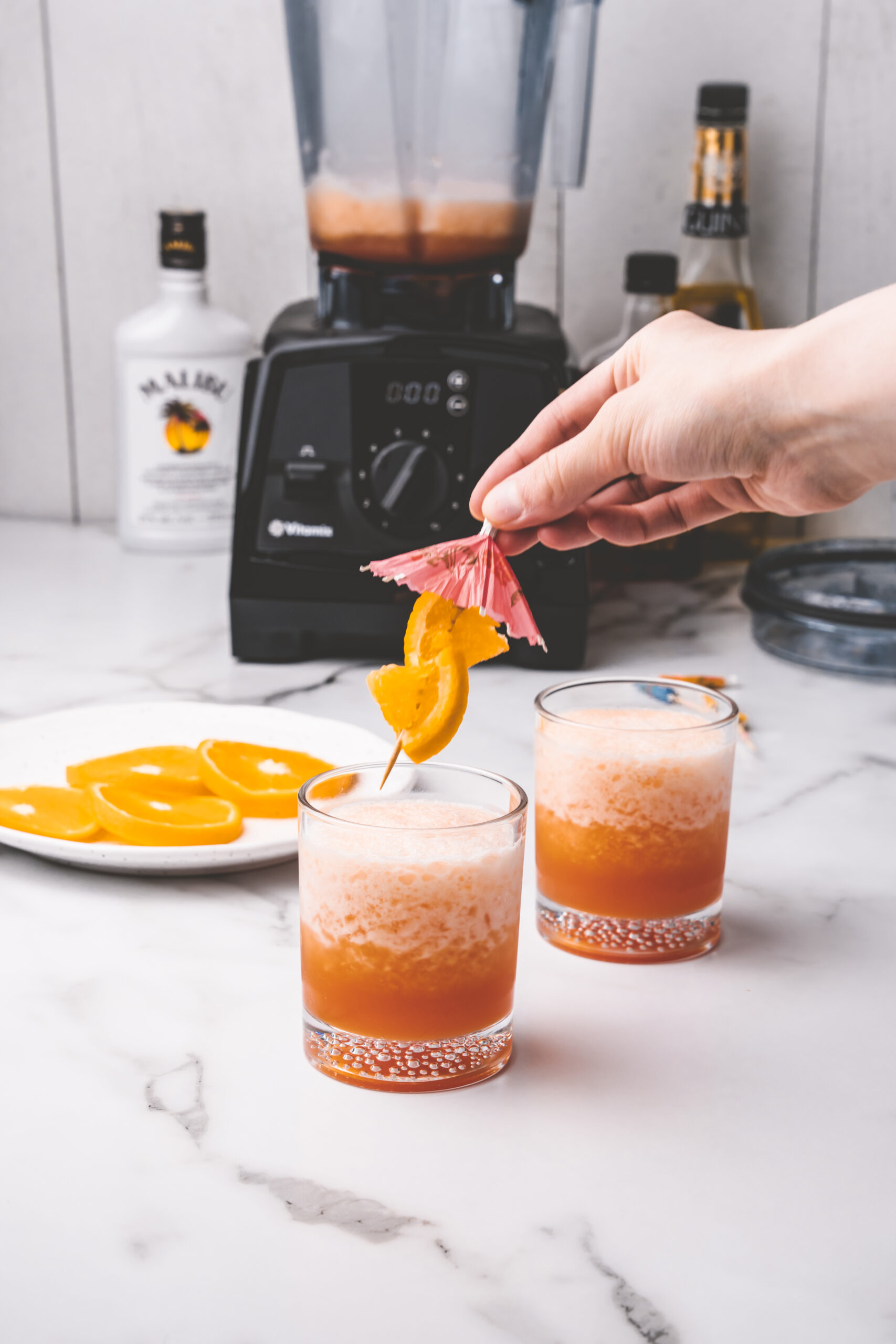 Hand placing garnish in cocktail glass. 