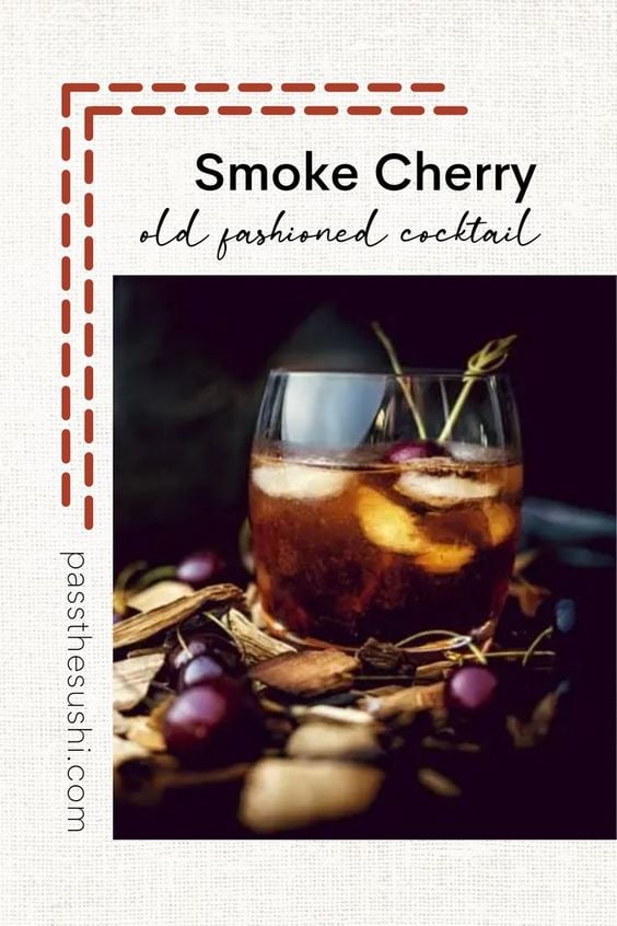 smoked cherry old fashioned cocktail in glass with cherry and wood chips surrounding it
