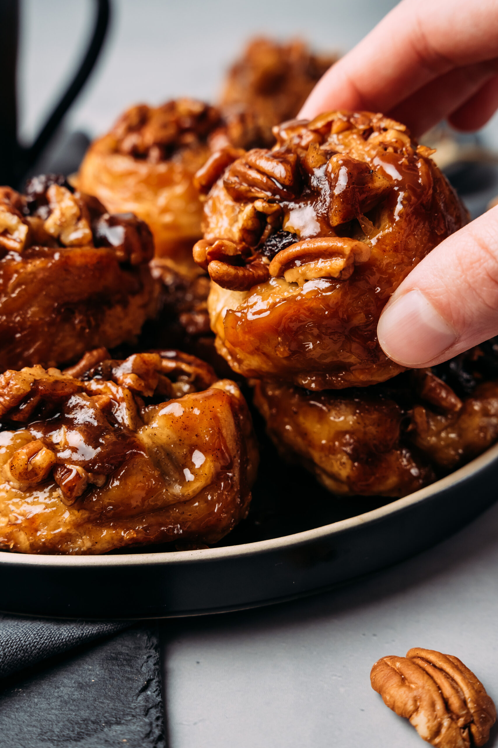 lifting a piece of sticky bun out of a pile