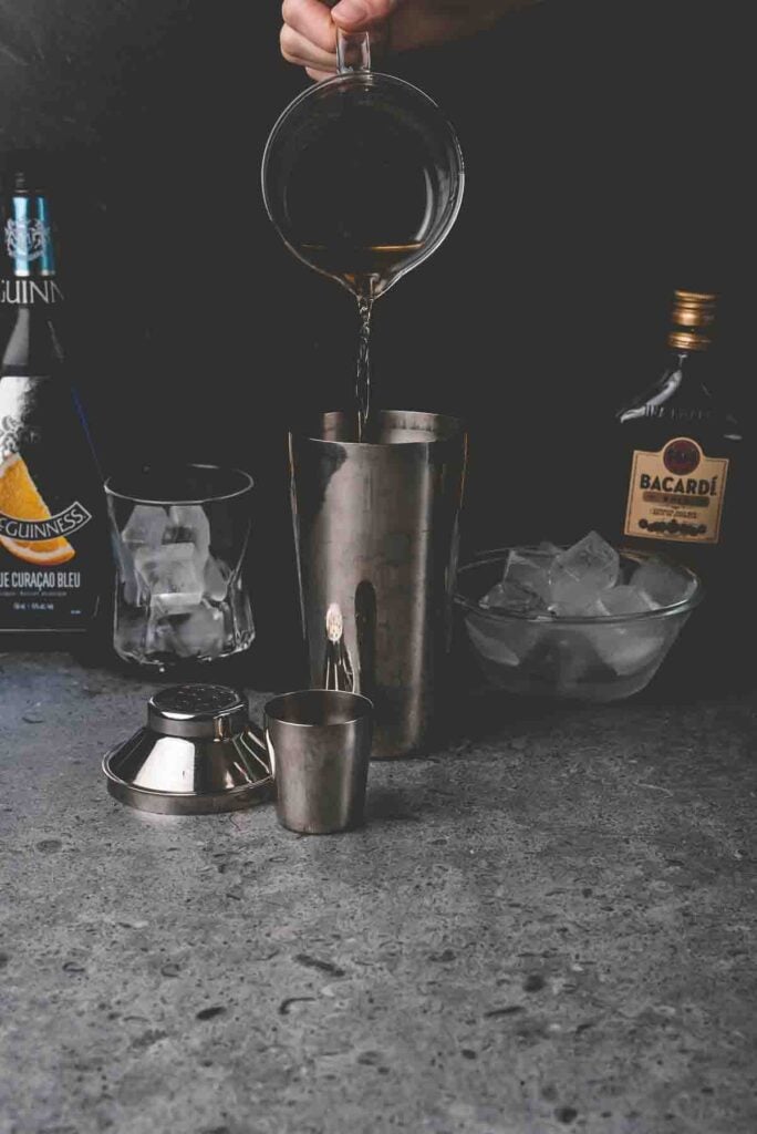 pouring drink mix into a metal shaker