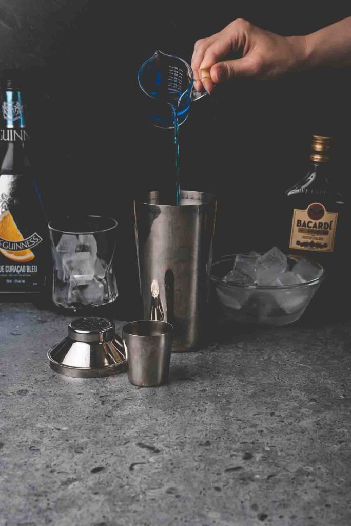 pouring drink mix into a metal shaker