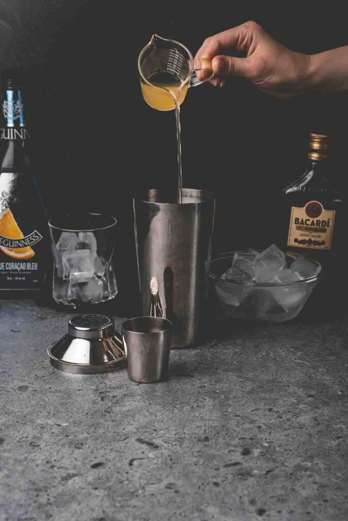 pouring drink mix into a metal shaker