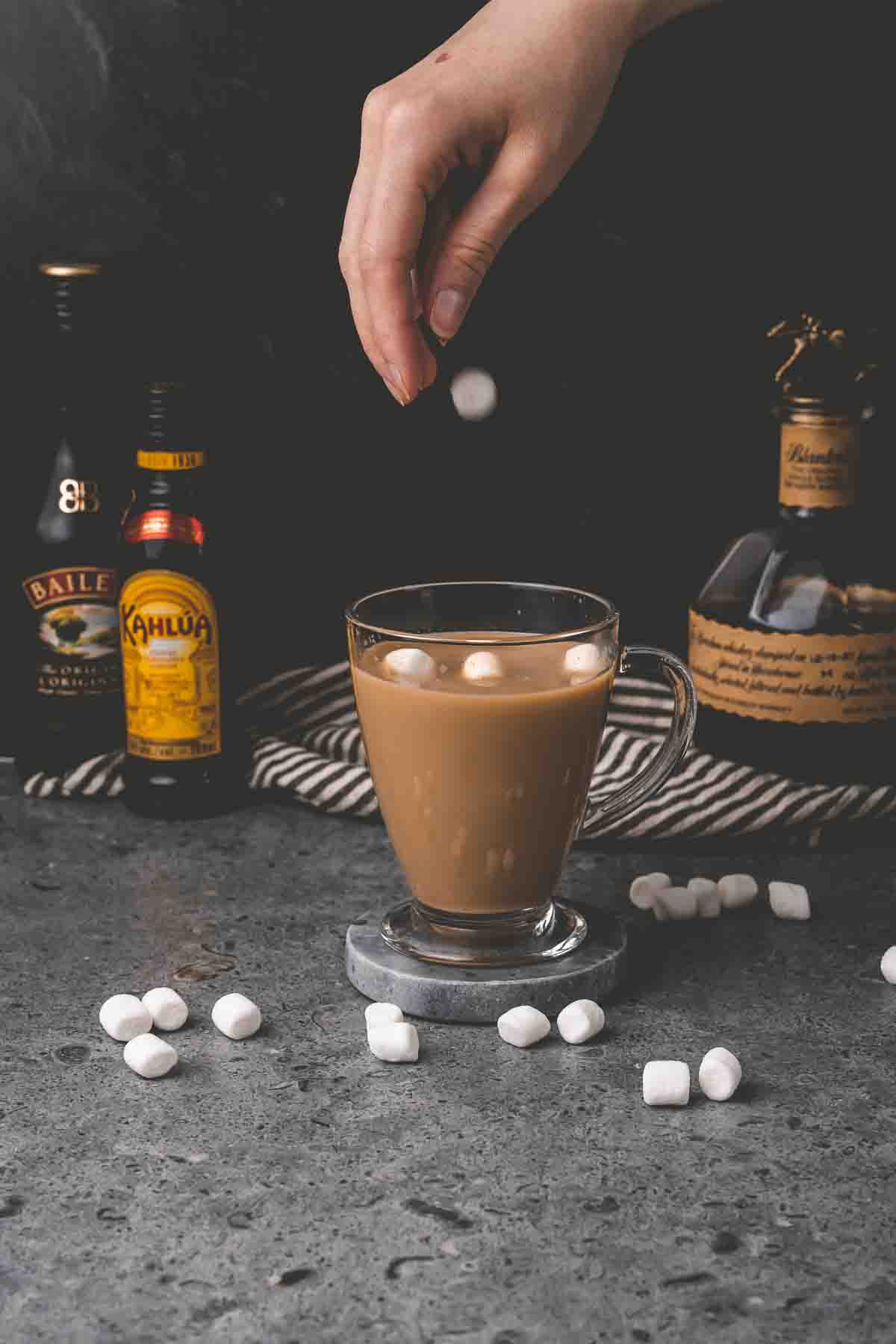 Hand dropping marshmallows into the glass. 