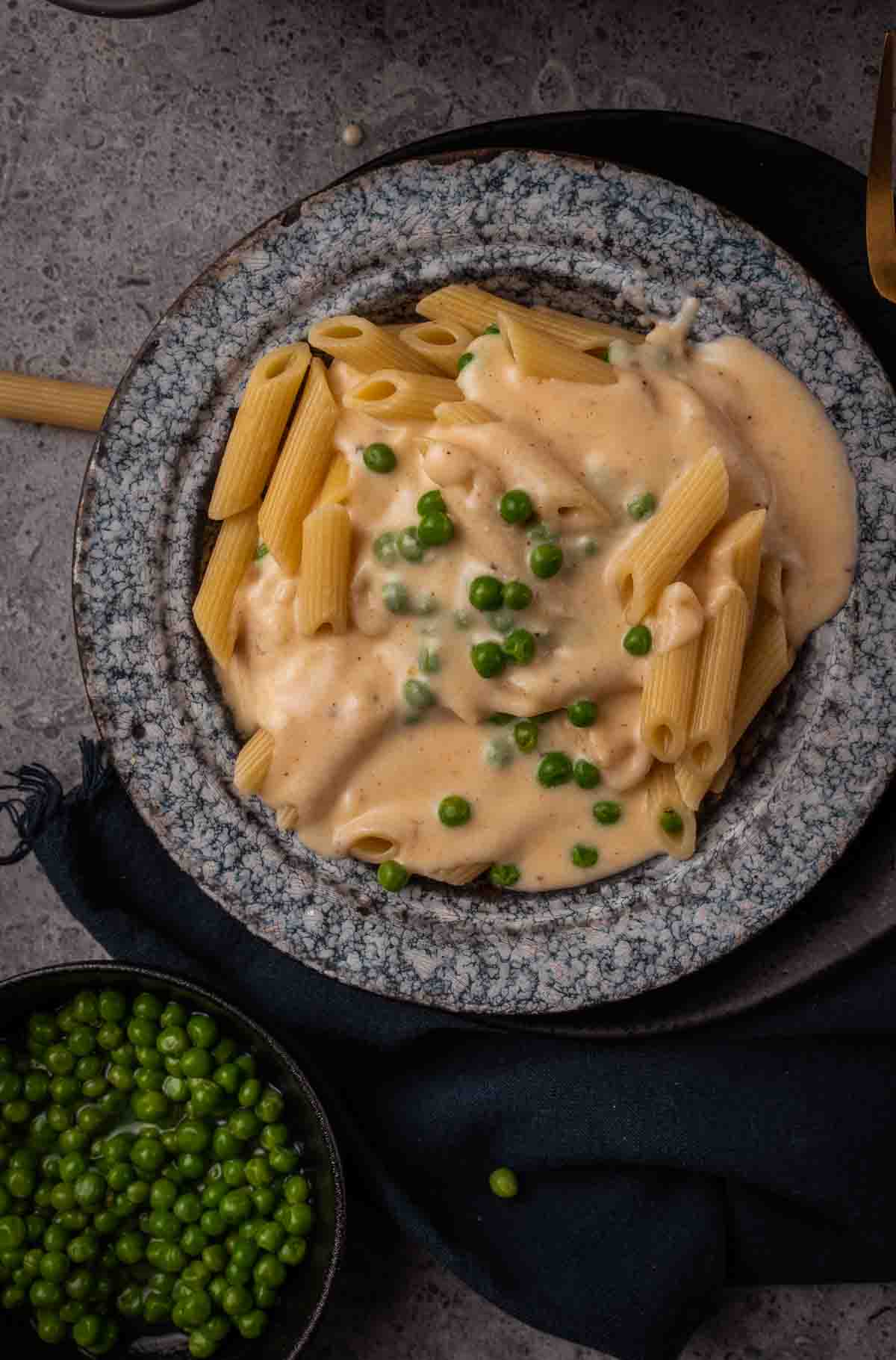 Bowl of pasta with cheese sauce and peas. 
