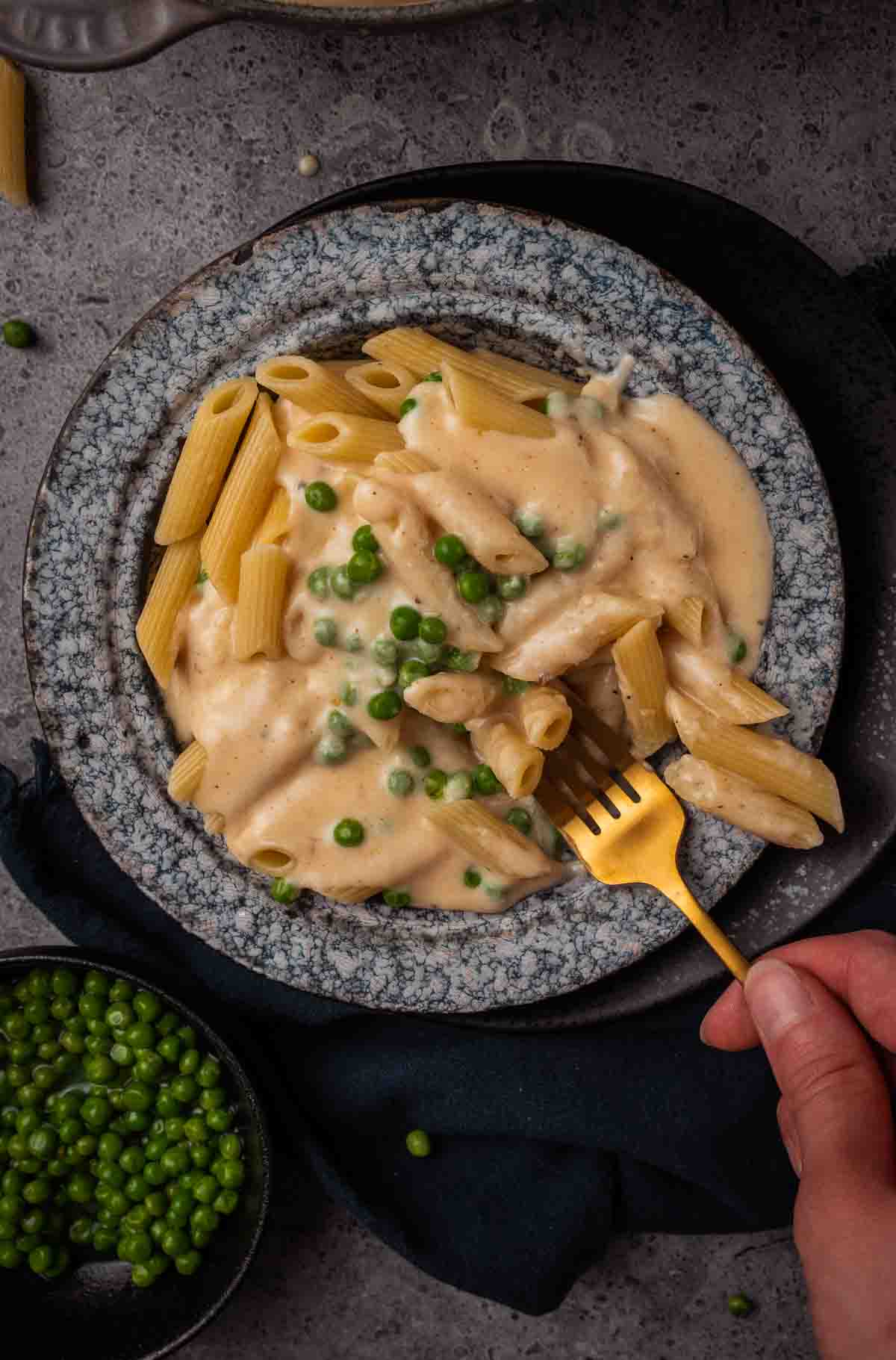 Fork poking into a creamy bowl of pasta.