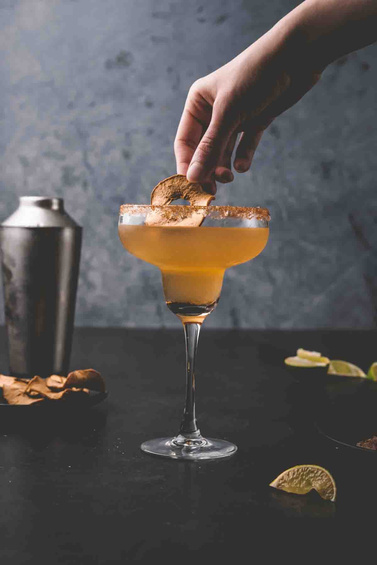 Hand placing garnish into margarita.