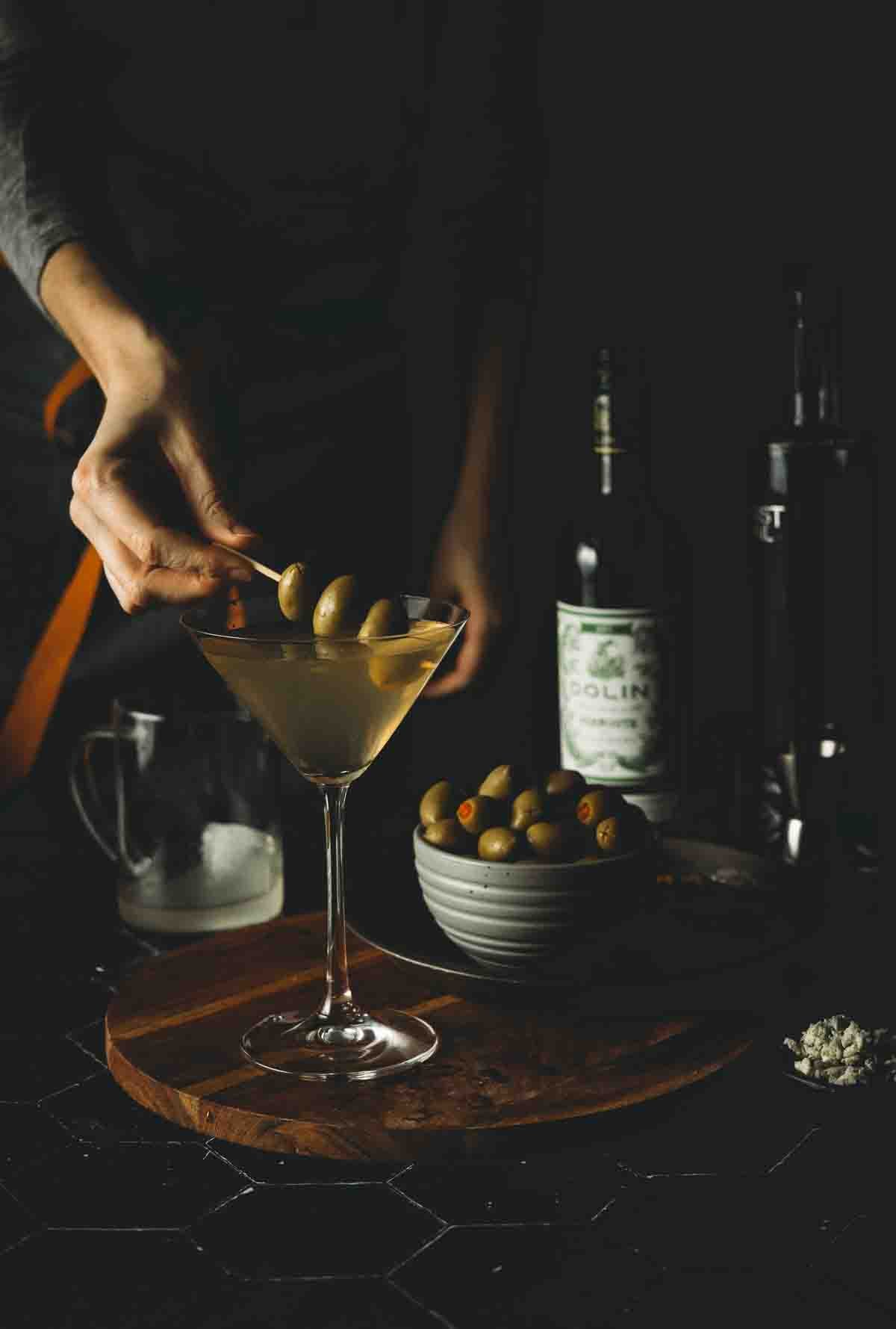 Hand placing garnish in martini. 