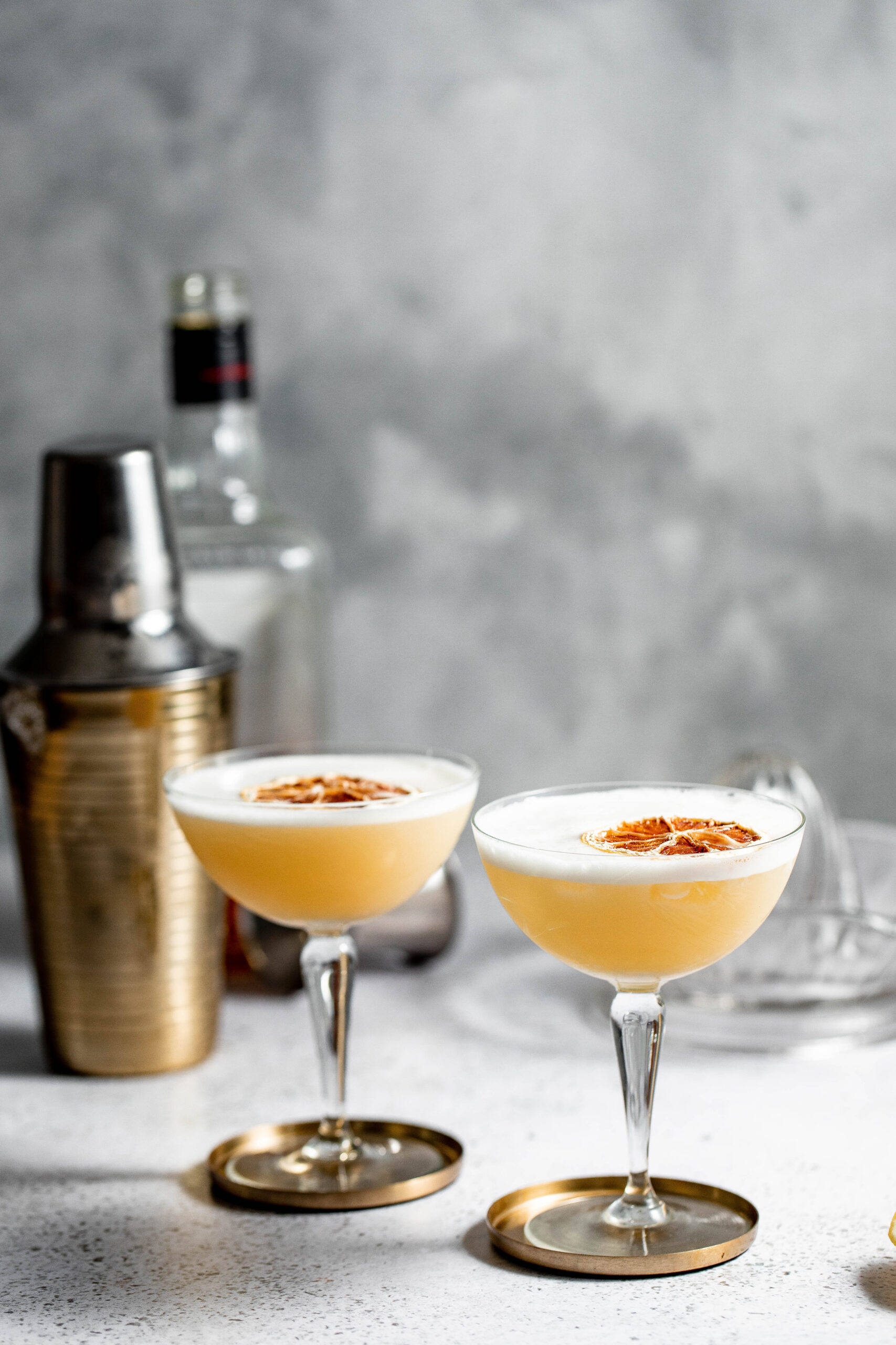 Two coupe glasses filled with frothy cocktails.