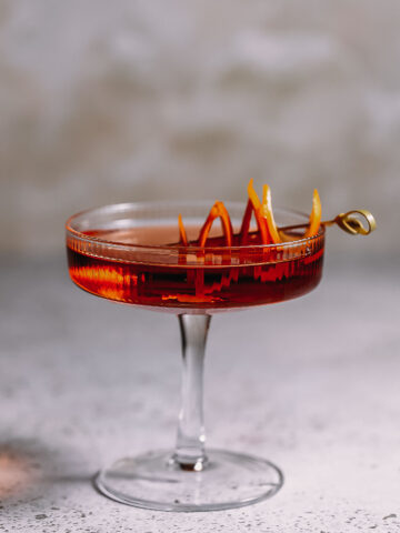 Side shot of a cocktail glass filled with a manhattan using brandy.