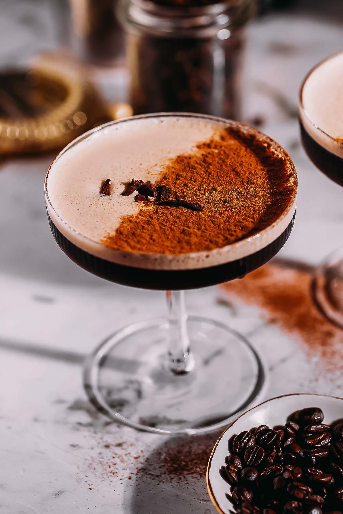 A coupe glass filled with a frothy espresso martini infused with chai spices.