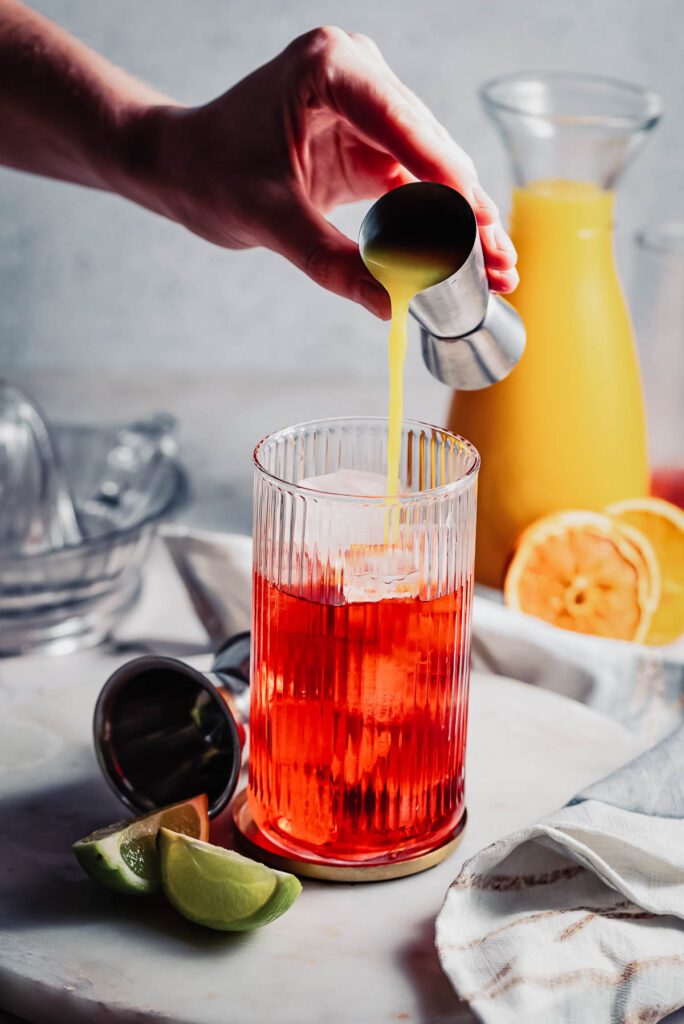 Orange juice being poured from a jigger. 