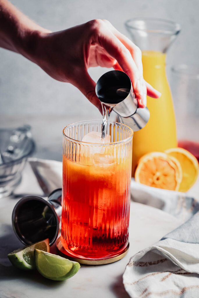 Hand pouring vodka into cocktail. 