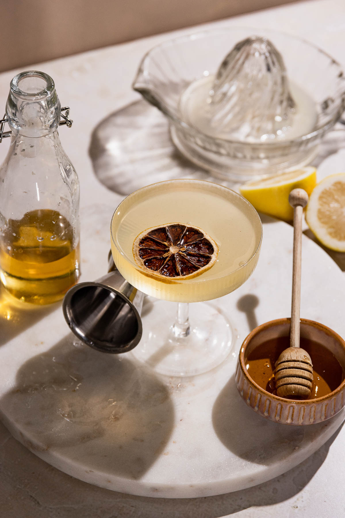 Table with coupe glass of gin and lemon bee's knees cocktail. 