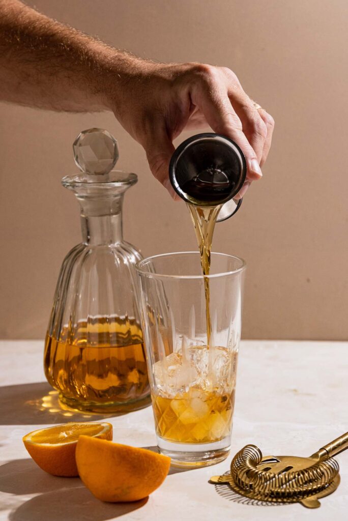 Bourbon being poured into a cocktail shaker. 