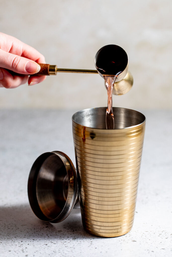 Brandy being poured into cocktail shaker. 