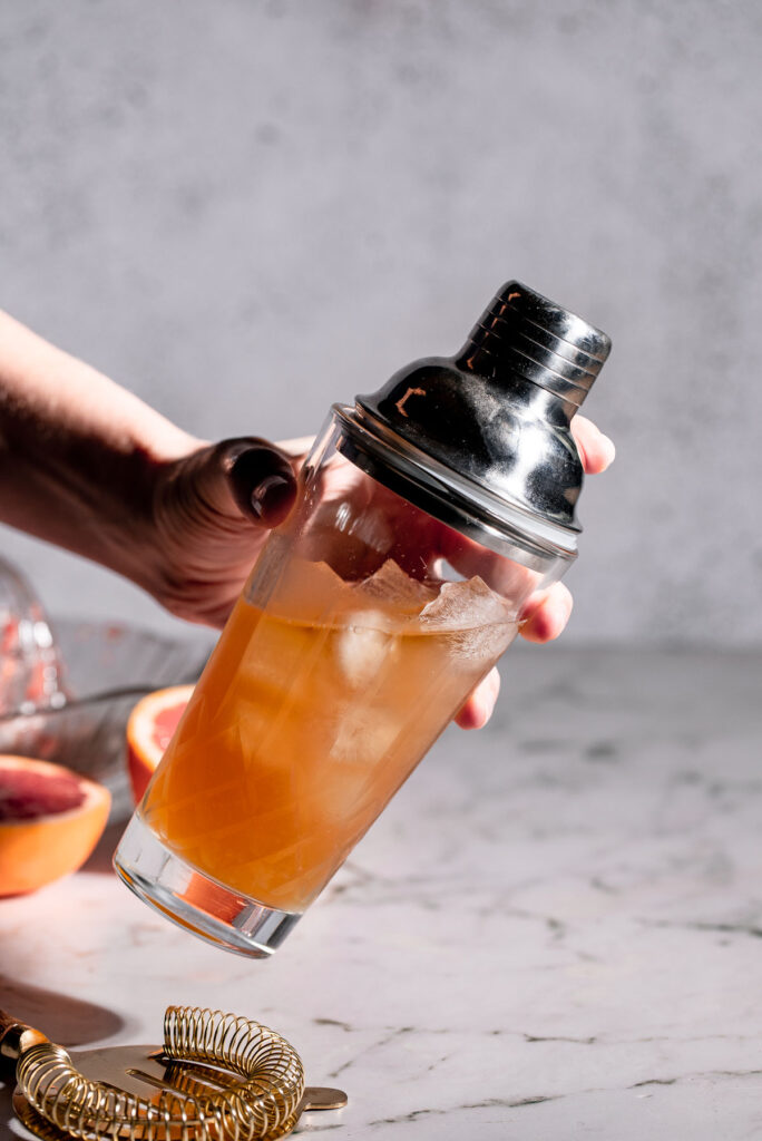 Cocktail shaker being held to shake. 