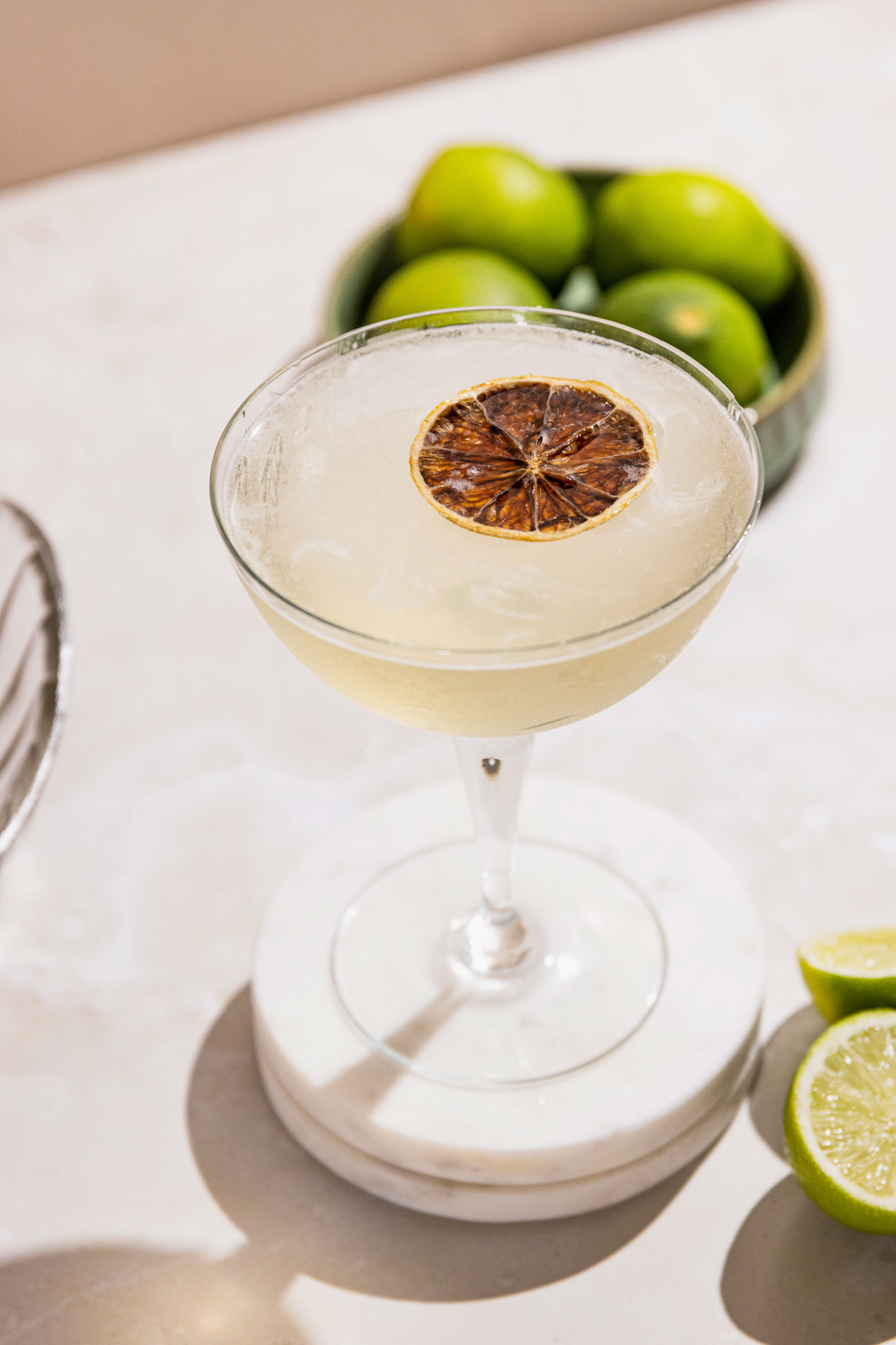 Gimelet cocktail from the top in a coupe glass with a dehydrated lime slice for garnish.