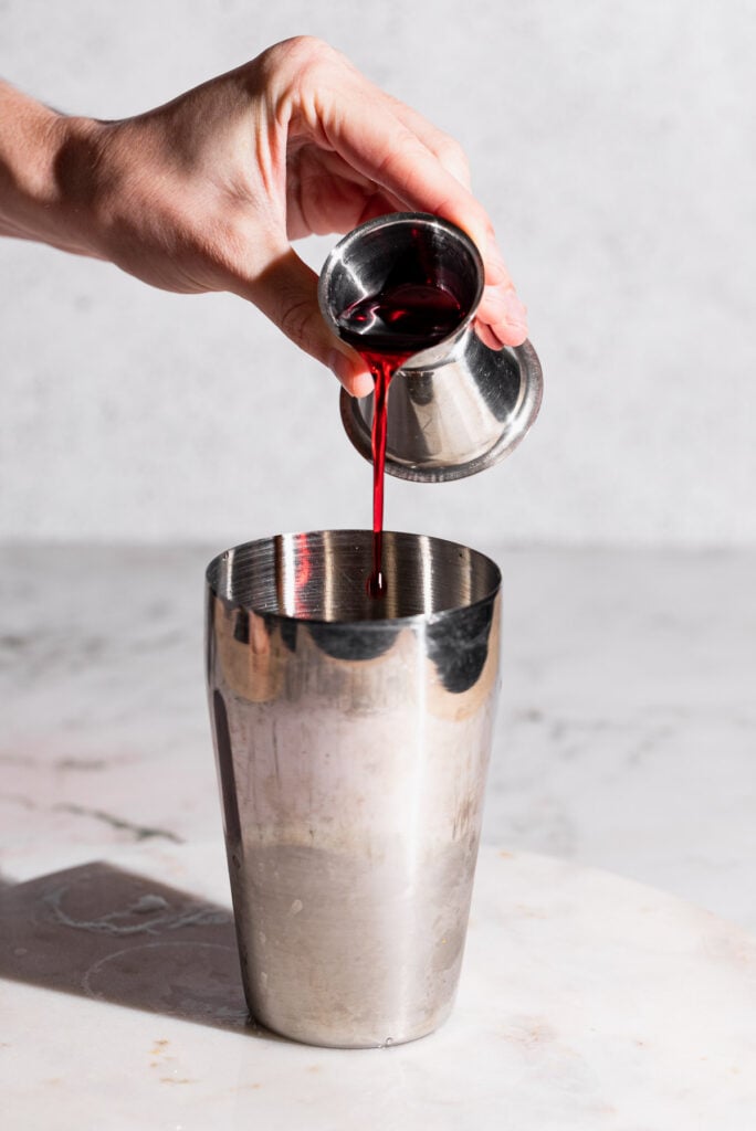 Grenadine pouring into a cocktail shaker.