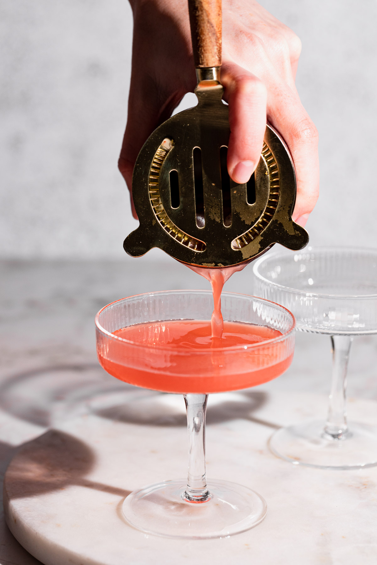 Mary pickford cocktail being strained from a cocktail shaker.