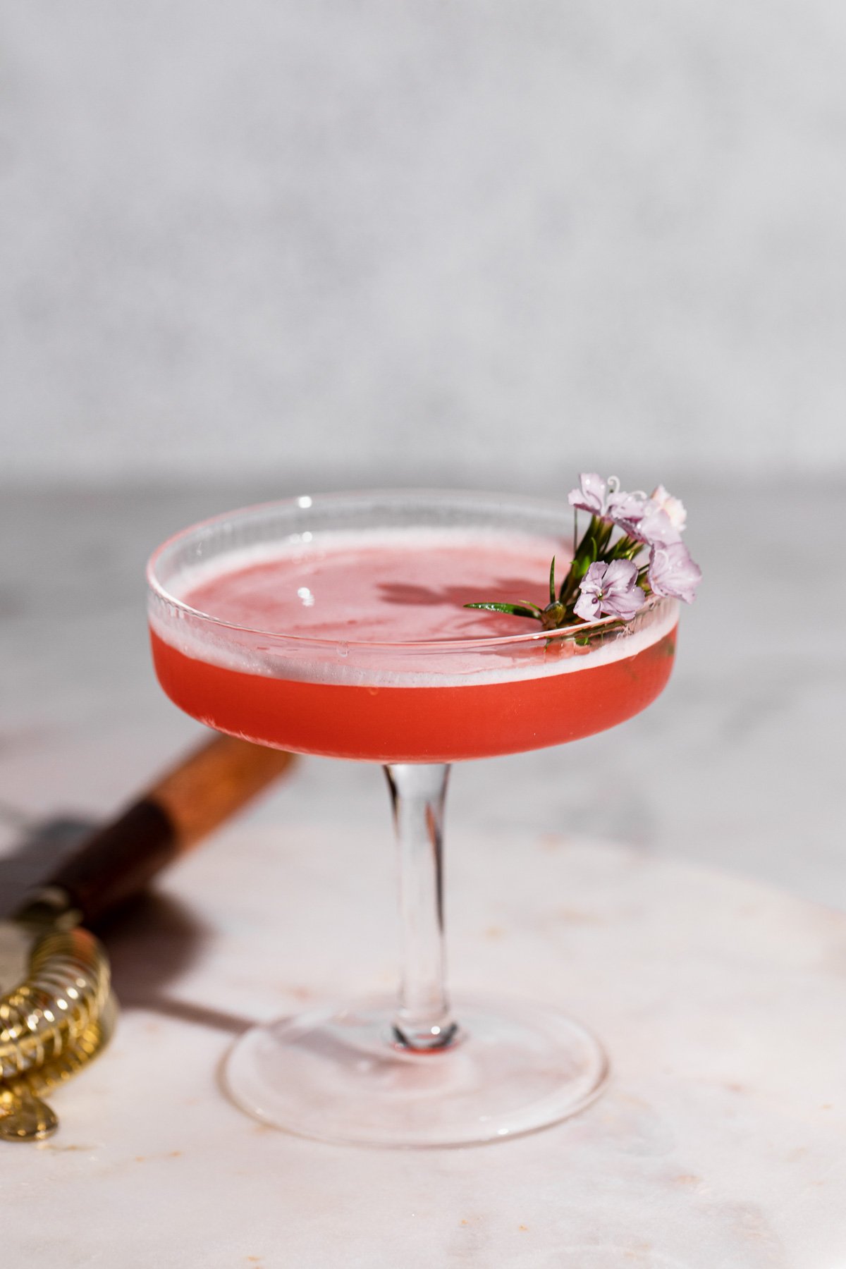 Side shot of a coupe glass filled with pink mary pickford cocktail.