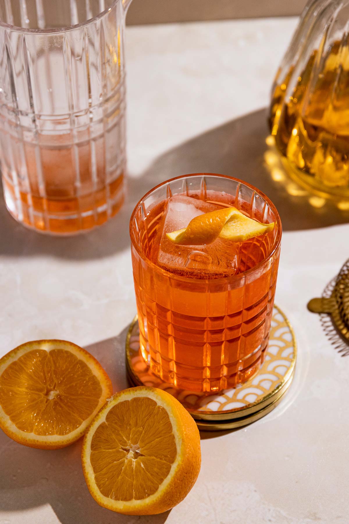 Bright crispy photo of a Negroni in a rocks glass with craft ice and an orange twist. 