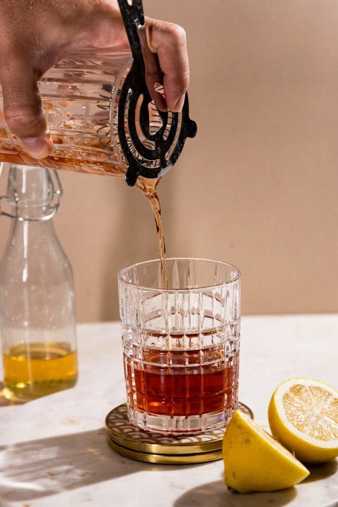 Cocktail being strained into a rocks glass.