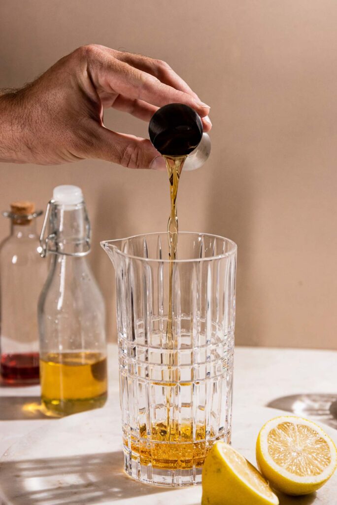 Rye whiskey being added to a cocktail shaker.