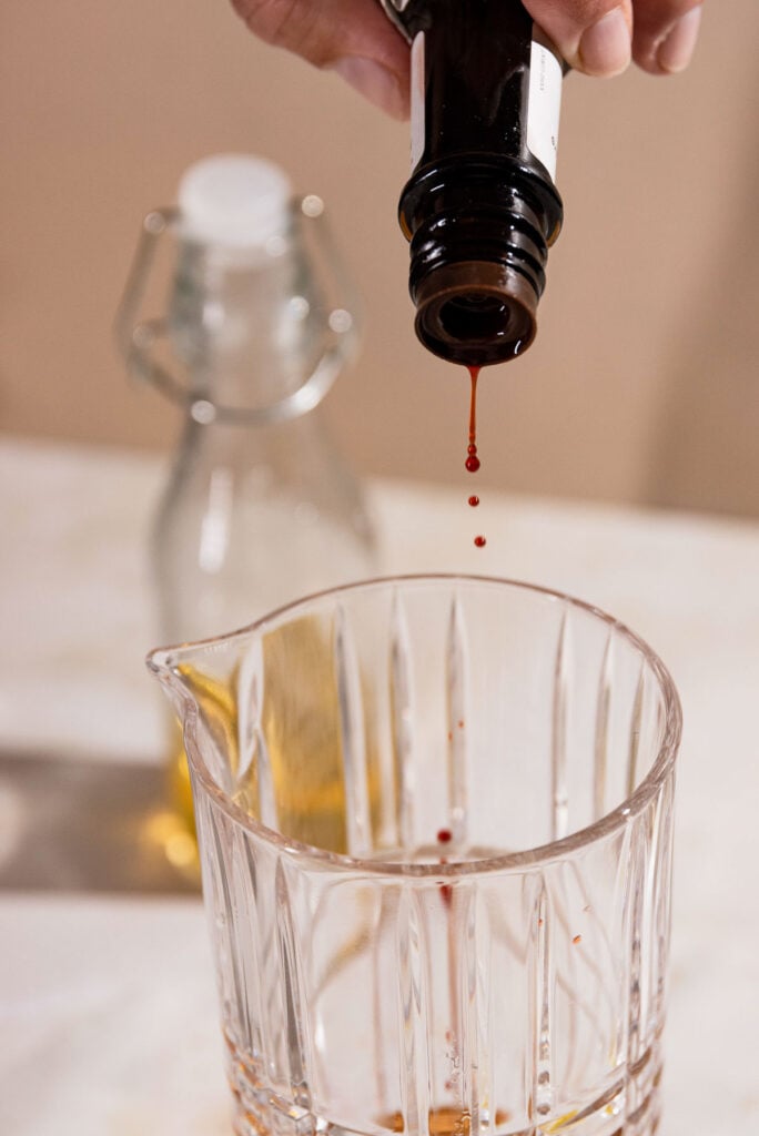 Bitters being dashed into a cocktail shaker. 