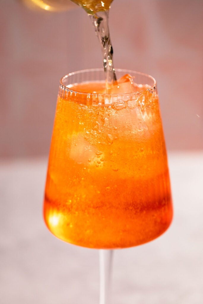 Close up of champagne being poured into the campari spritz.