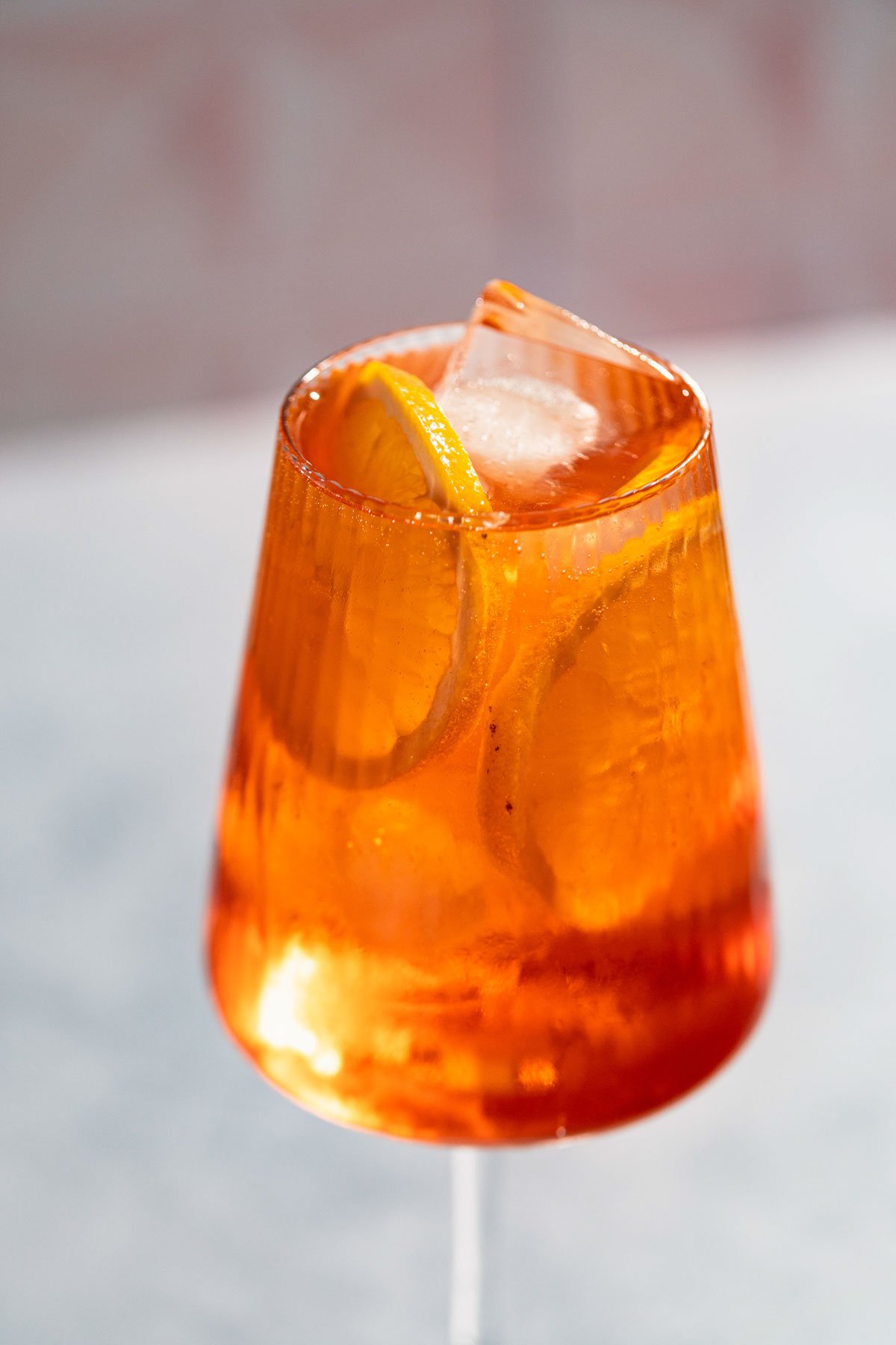 Vibrant orange campari spritz cocktail in a wine glass filled to the rim. 