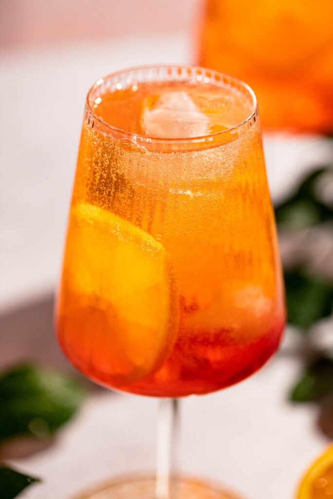 Wine glass filled with the cocktail and garnished with orange slices. 