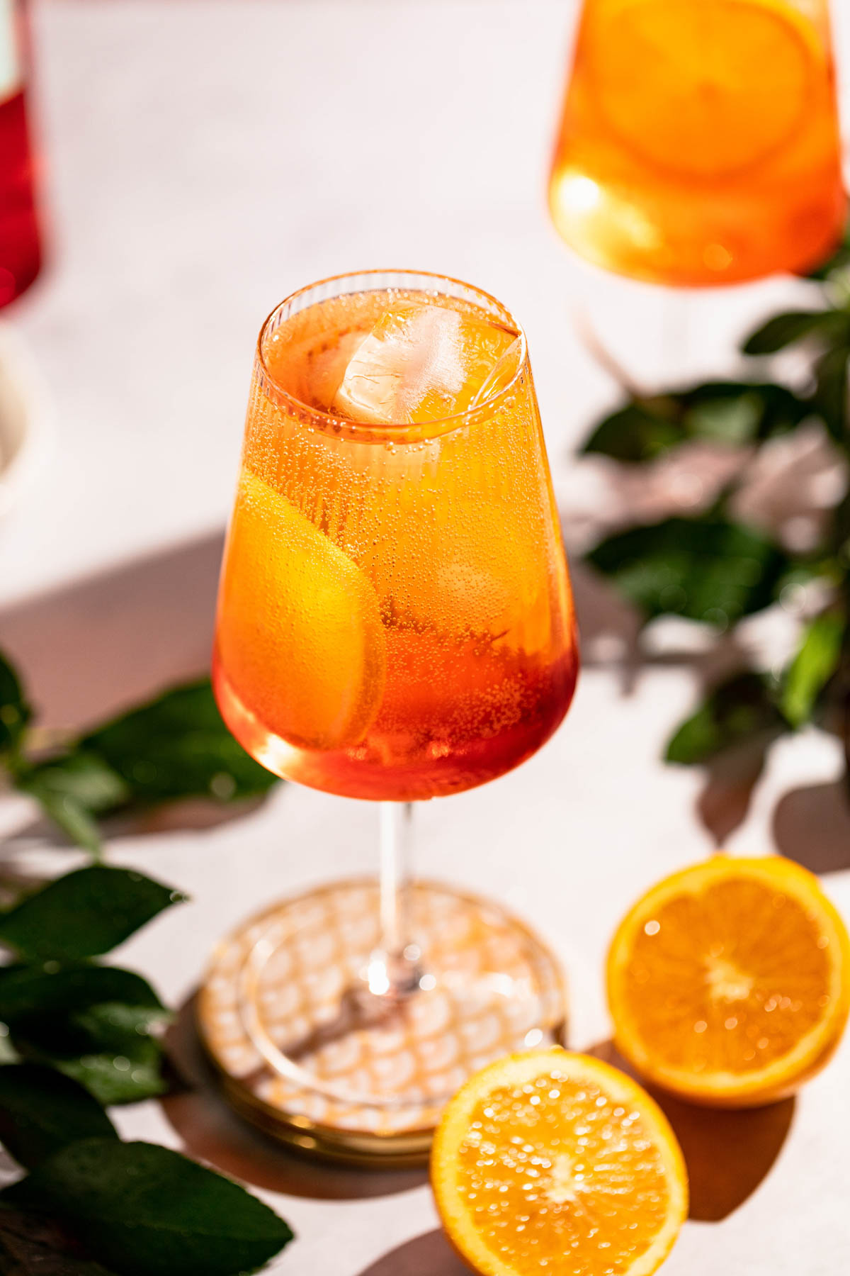 Bright orange bubbly cocktail in a wine glass with ice and orange slices. 