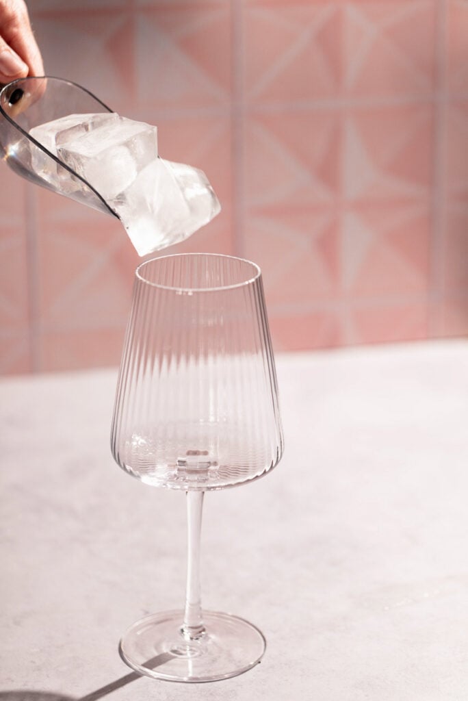 Ice being added to a wine glass.