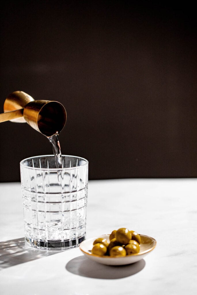 Gin being added to a cocktail glass. 