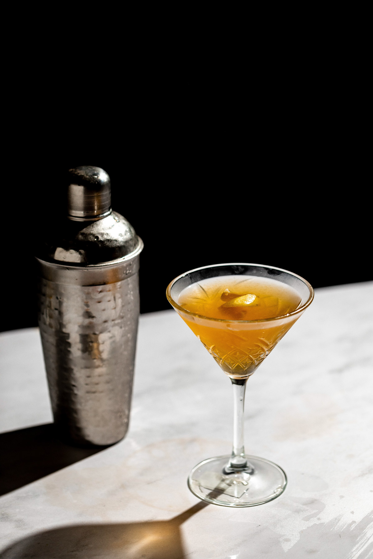 Earl grey martini and cocktail shaker resting on a white table. 