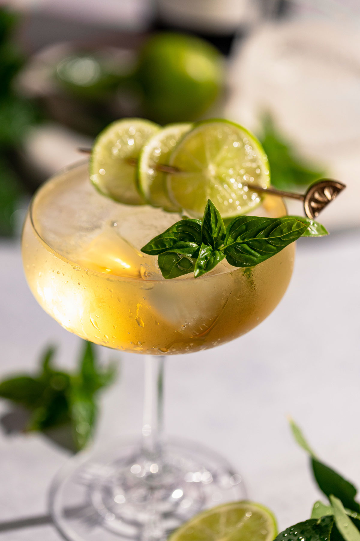 Close up of the hugo spritz cocktail with garnish of lime and basil.