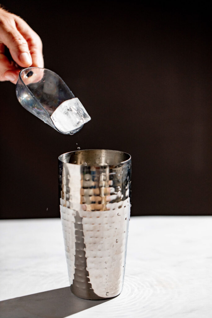 Ice being added to a cocktail shaker.