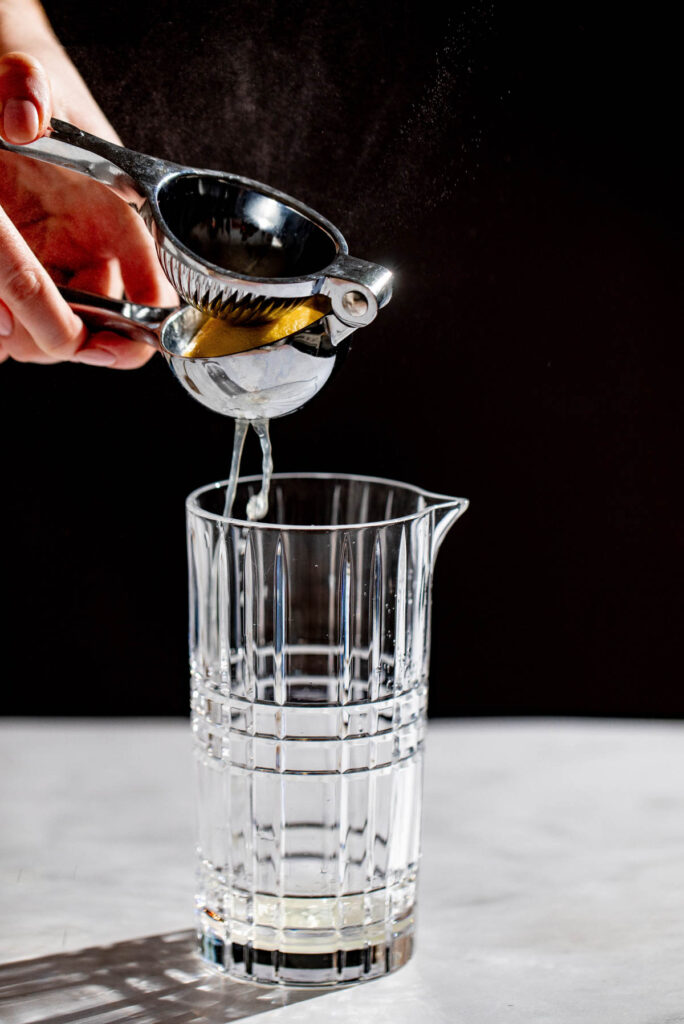 Lemon juice being added to a cocktail glass. 