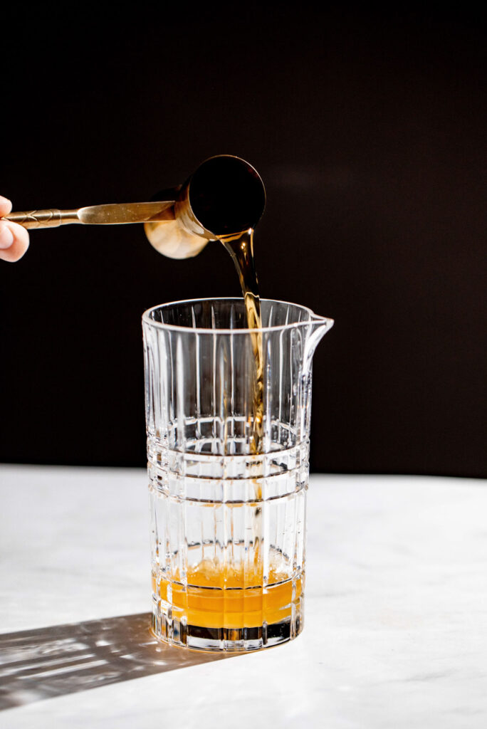 Cognac being added to a cocktail glass.  