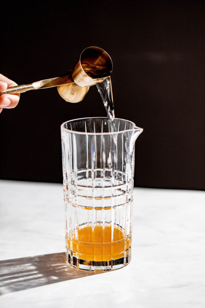 Orange liquor being added to a cocktail glass. 