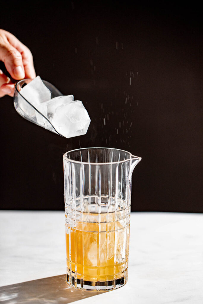 Ice being added to the cocktail shaker with a splash. 